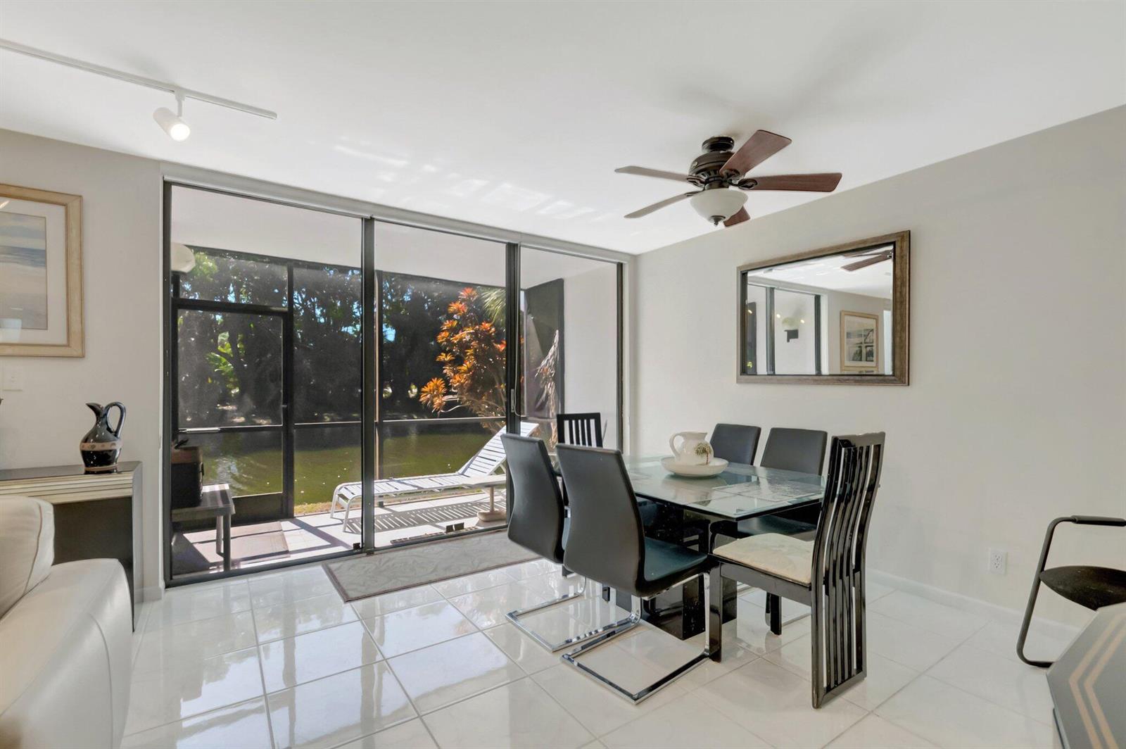 A dining room with a glass table, black chairs, tile floors, and a sliding glass door — 3705 Bridgewood Drive, Boca Raton FL 33434, BOCA RATON, FL
