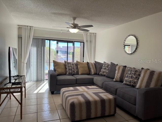 A living room features a gray sectional sofa, a patterned ottoman, and a ceiling fan — 23465 HARBORVIEW ROAD UNIT 1006, PUNTA GORDA, FL