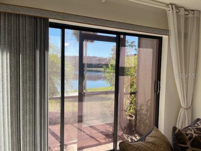 A sliding glass door opens to a screened patio overlooking a pond and landscaping — 23465 HARBORVIEW ROAD UNIT 1006, PUNTA GORDA, FL