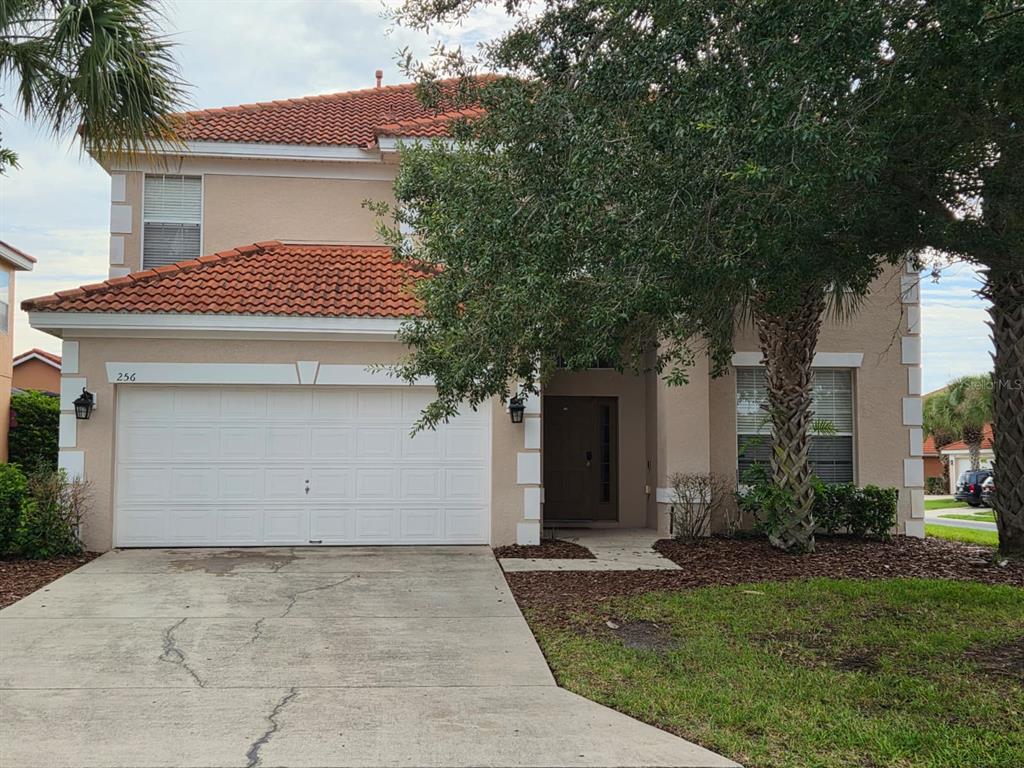 A two-story house with a tan stucco exterior, a tile roof, and a two-car garage — 256 SEVILLA AVENUE, DAVENPORT, FL