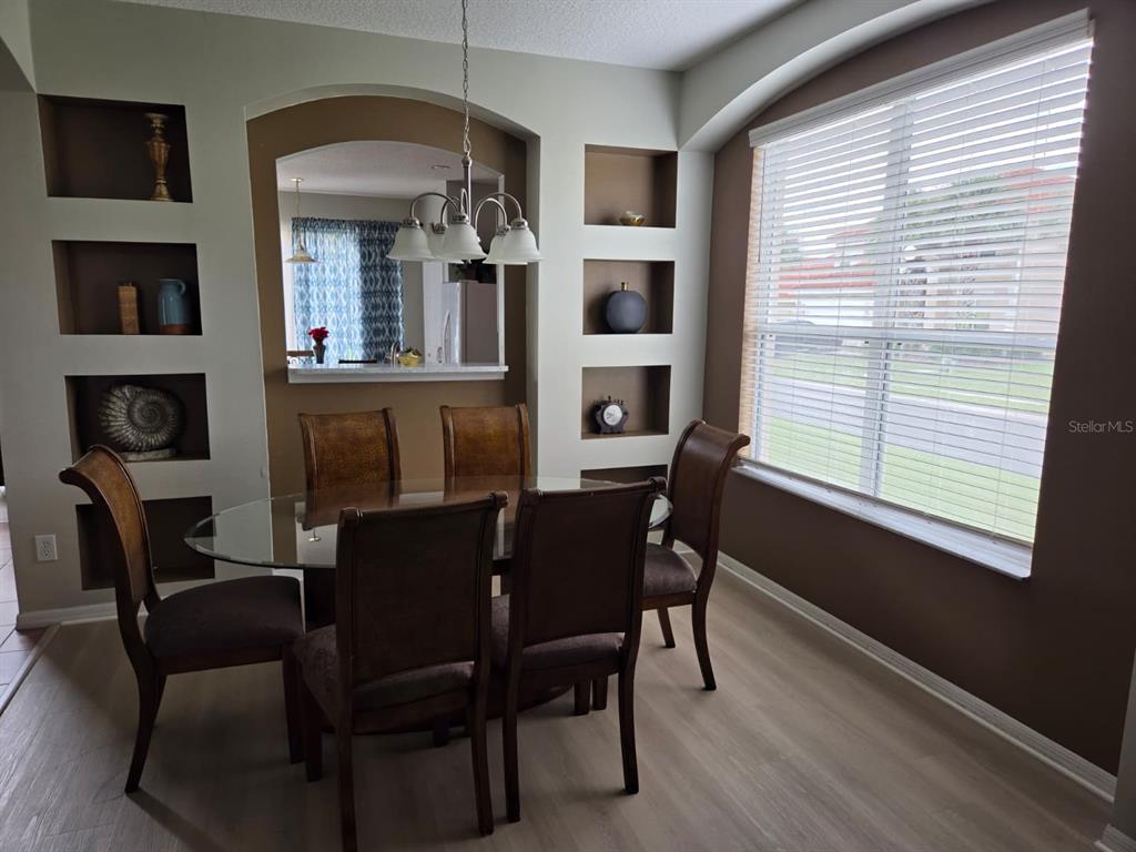 A dining room with a glass table, six chairs, built-in wall niches, and a large window — 256 SEVILLA AVENUE, DAVENPORT, FL