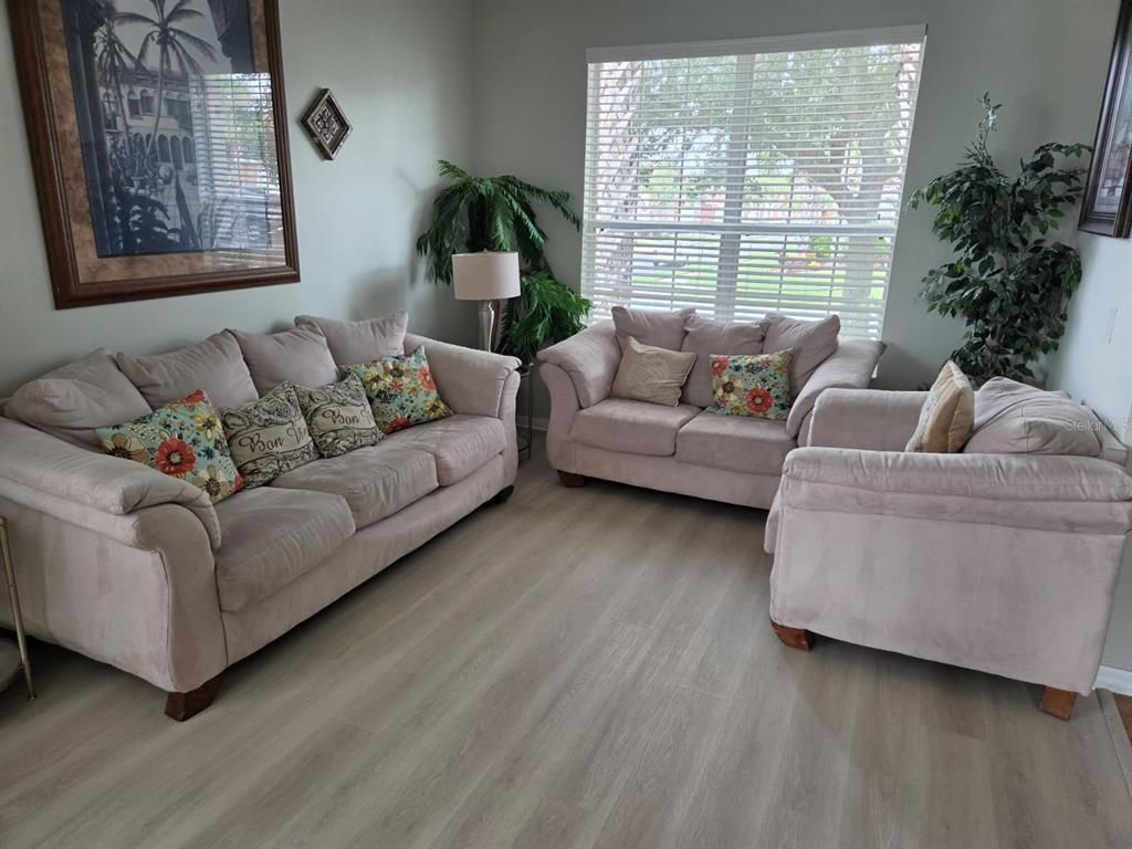 A living room features a light-colored sofa, loveseat, and armchair on wood-look flooring — 256 SEVILLA AVENUE, DAVENPORT, FL