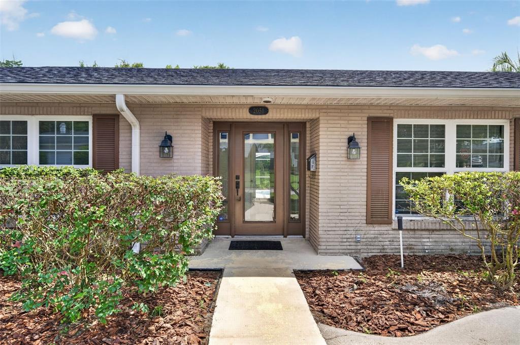 The exterior of a single-story brick house features a brown front door and brown shutters — 2051 DYAN WAY, MAITLAND, FL
