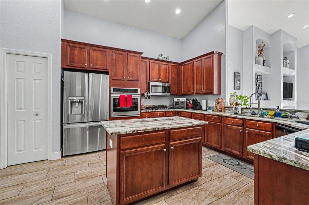 A dining area with a wooden table and chairs opens into a kitchen and living room — 12515 BURGESS HILL DRIVE, RIVERVIEW, FL