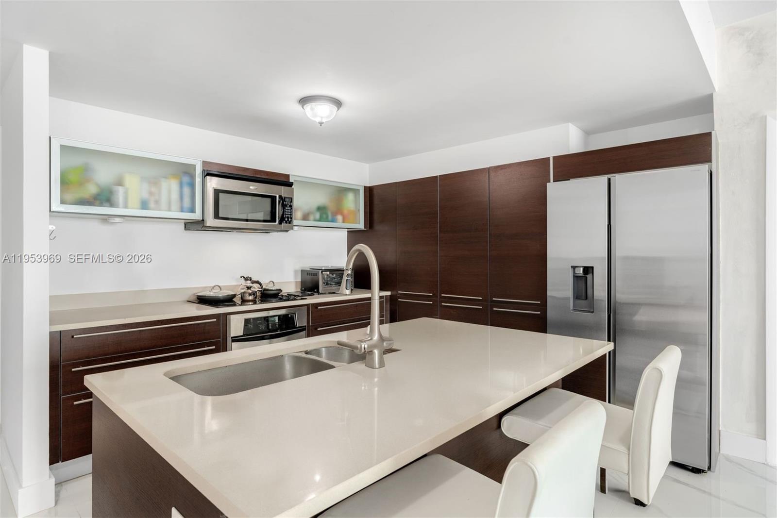 A modern kitchen features dark wood cabinetry, a large quartz island, and stainless steel appliances — 1900 N Bayshore Dr # 3202, Miami FL 33132, MIAMI, FL