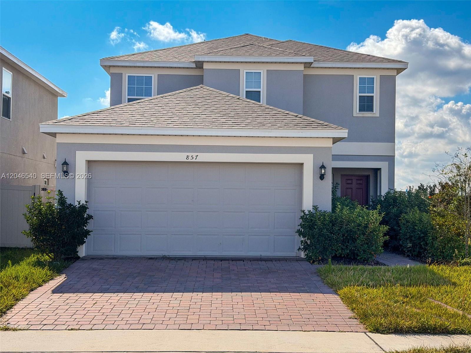 A two-story house features a gray exterior, a two-car garage, and a brick driveway — 857 scrub oak hammock rd, Davenport FL 33837, DAVENPORT, FL
