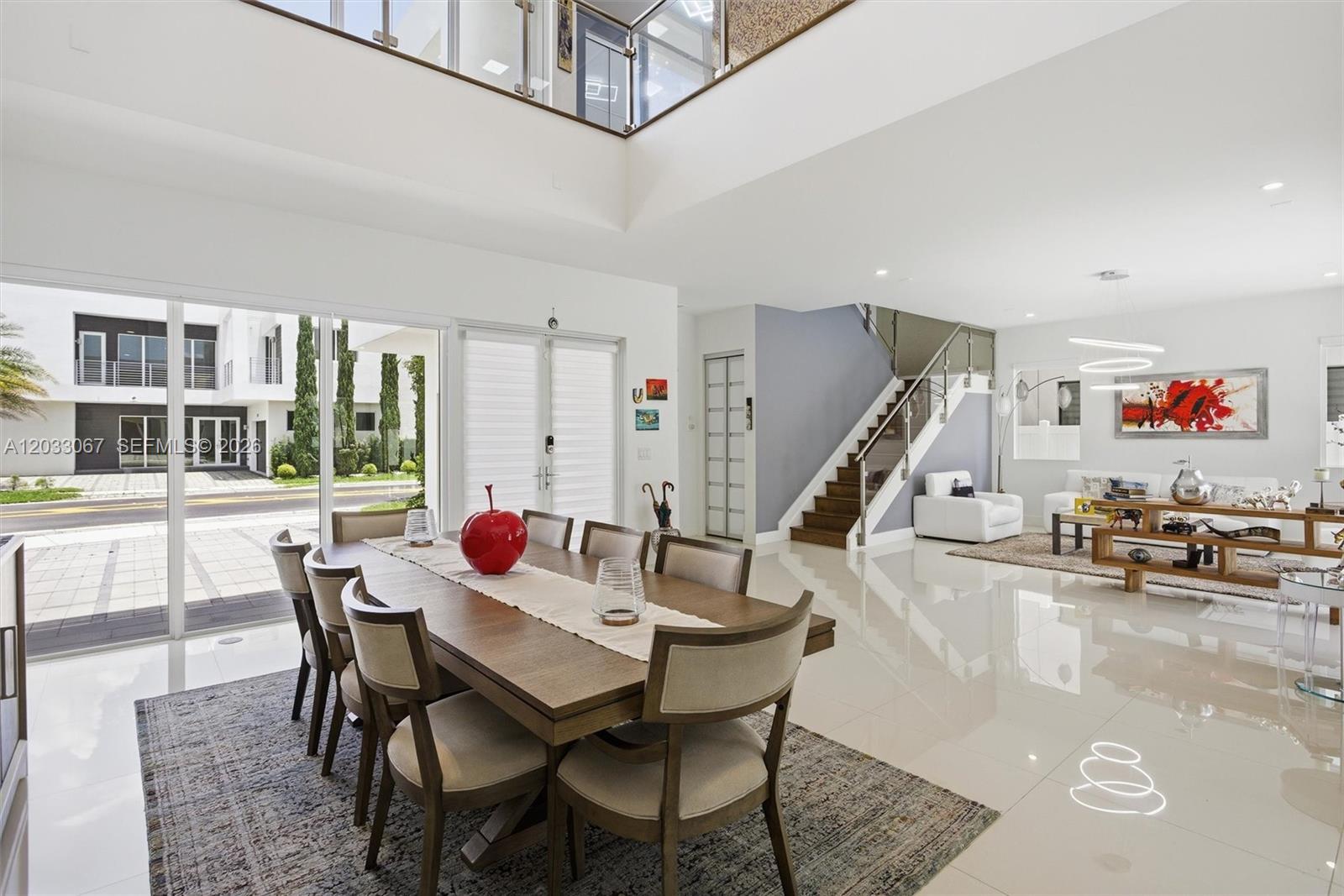 A dining area with a wooden table and chairs opens to a living room with stairs — 7472 NW 100th Ave, Doral FL 33178, DORAL, FL
