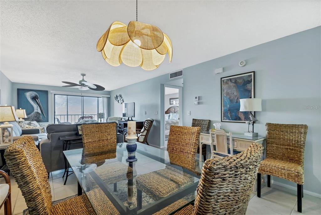 A dining area with a glass table and wicker chairs sits before a living room — 14459 RIVER BEACH DRIVE UNIT 129, PORT CHARLOTTE, FL