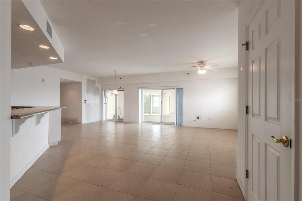 An open-concept living and dining area features tile flooring, a breakfast bar, and sliding doors — 5300 S ATLANTIC AVENUE UNIT 3-605, NEW SMYRNA BEACH, FL