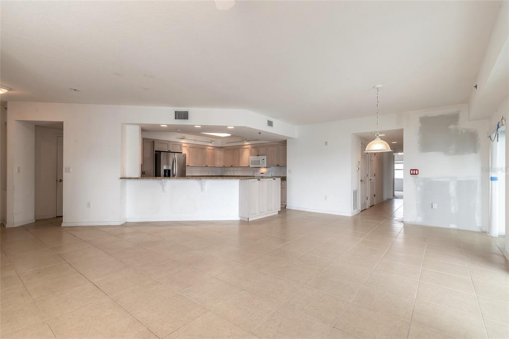 An open-concept living area features light tile flooring, a kitchen with wood cabinets, and countertops — 5300 S ATLANTIC AVENUE UNIT 3-605, NEW SMYRNA BEACH, FL