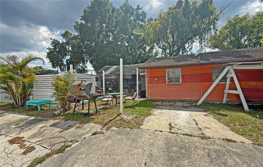 A backyard features a concrete patio, an orange house, a grill, and a swing set — 3511 E 23RD AVENUE, TAMPA, FL