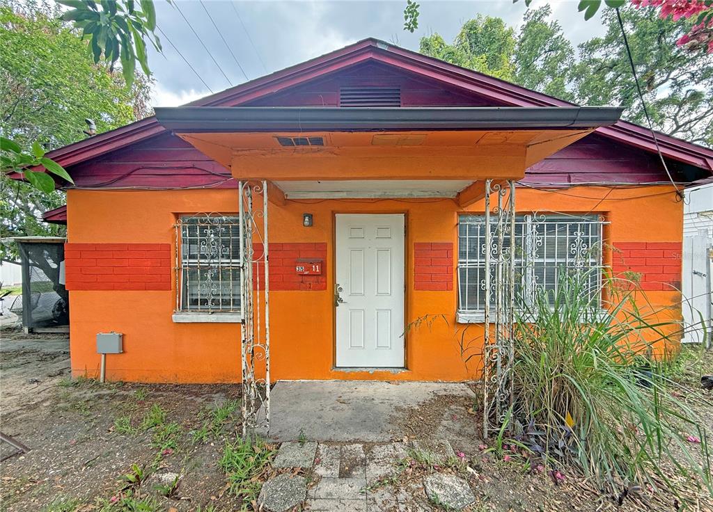 A single-story house with orange stucco walls, a red roof, and white security bars — 3511 E 23RD AVENUE, TAMPA, FL