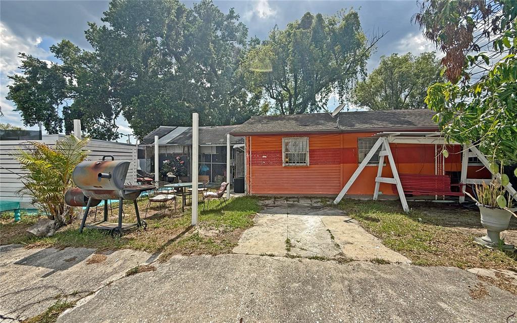 The exterior of a house features orange siding, a concrete patio, and a metal swing — 3511 E 23RD AVENUE, TAMPA, FL