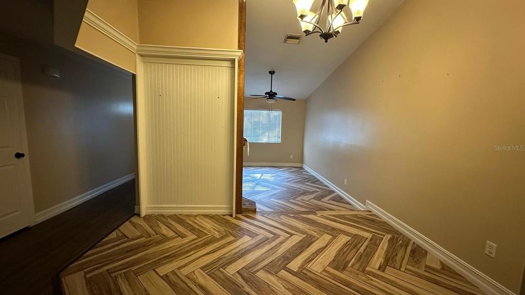 A room with herringbone-patterned wood flooring, a ceiling fan, and a chandelier — 102 WINDING RIDGE DRIVE, SANFORD, FL
