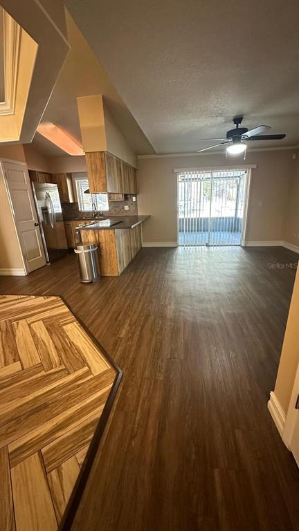 An open-concept kitchen with wood-look cabinets and flooring leads to a sliding glass door — 102 WINDING RIDGE DRIVE, SANFORD, FL