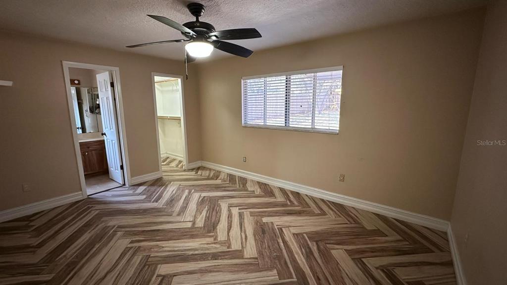 A bedroom with a ceiling fan, herringbone-patterned flooring, a window, and two doorways — 102 WINDING RIDGE DRIVE, SANFORD, FL