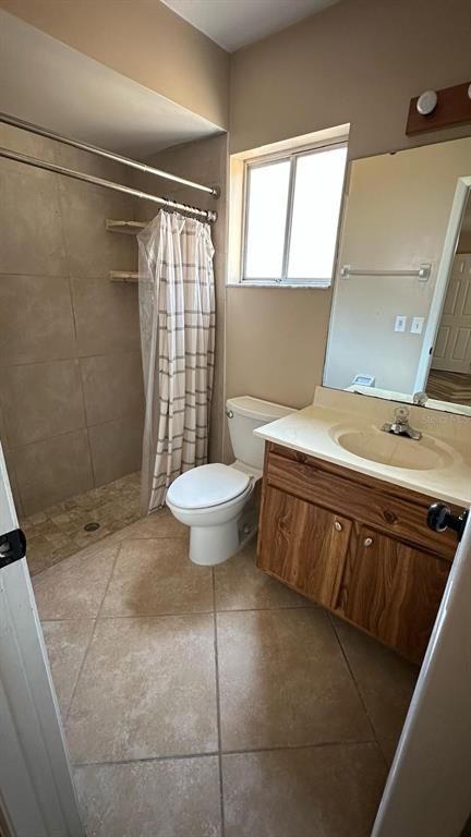 A bathroom features a tiled walk-in shower, a toilet, and a wooden vanity with sink — 102 WINDING RIDGE DRIVE, SANFORD, FL