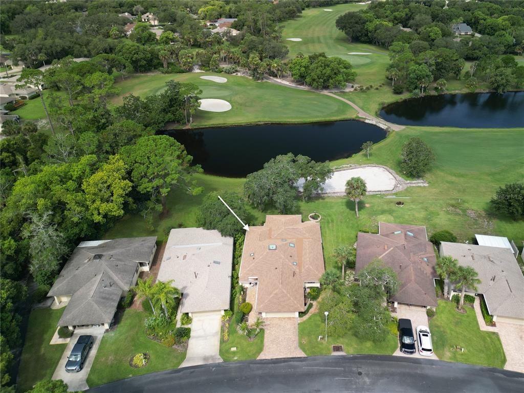 An aerial view shows a residential house with a tan roof overlooking a golf course — 214 CANTERBURY CIRCLE, NEW SMYRNA BEACH, FL