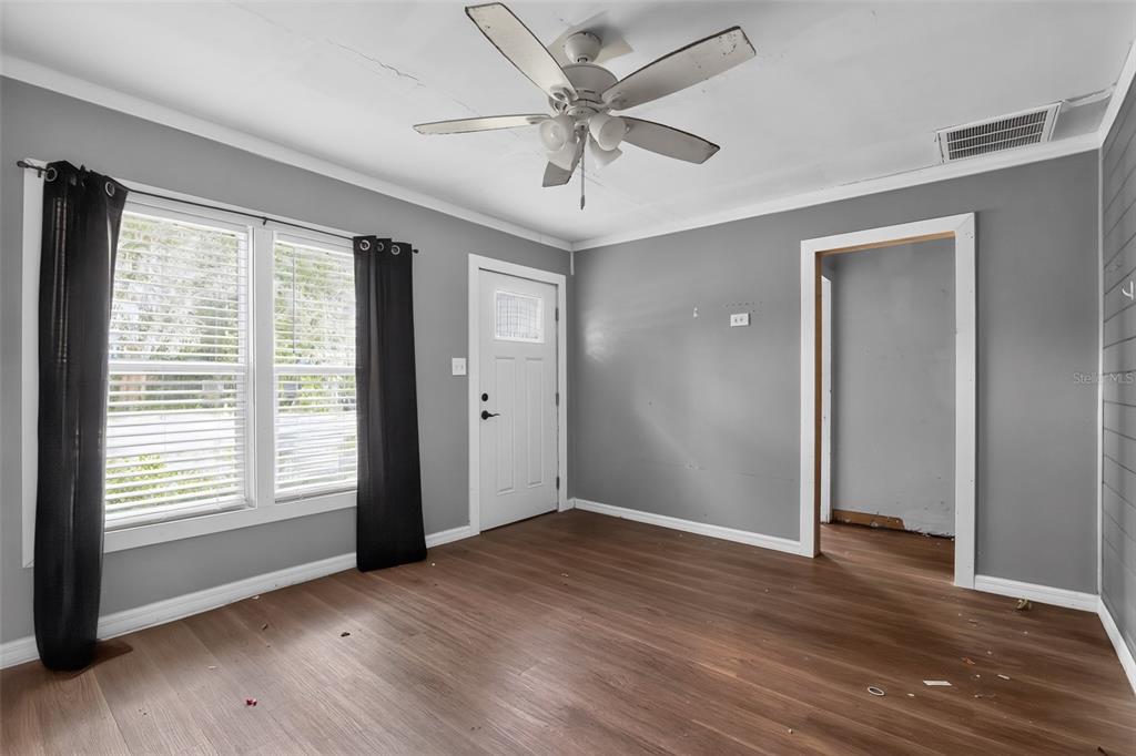 An empty room with gray walls, wood-look flooring, a ceiling fan, and a white door — 306 SE 2ND STREET, WILLISTON, FL