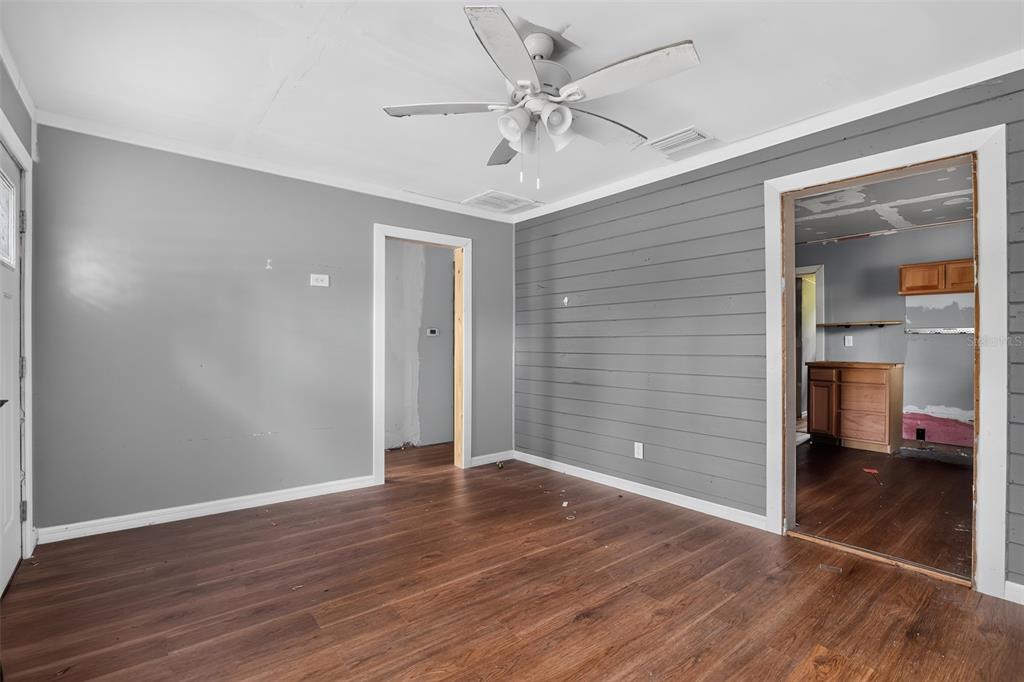 A room with wood-look flooring, gray walls, a shiplap accent wall, and a ceiling fan — 306 SE 2ND STREET, WILLISTON, FL