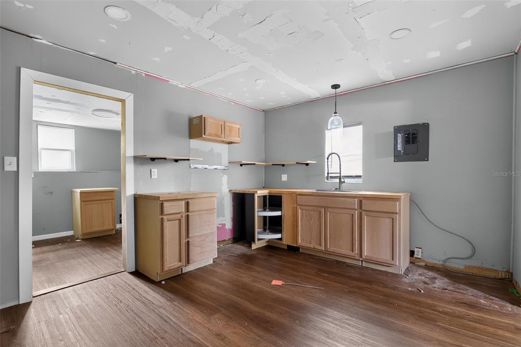 An unfinished kitchen features light wood cabinets, open shelving, and gray walls — 306 SE 2ND STREET, WILLISTON, FL