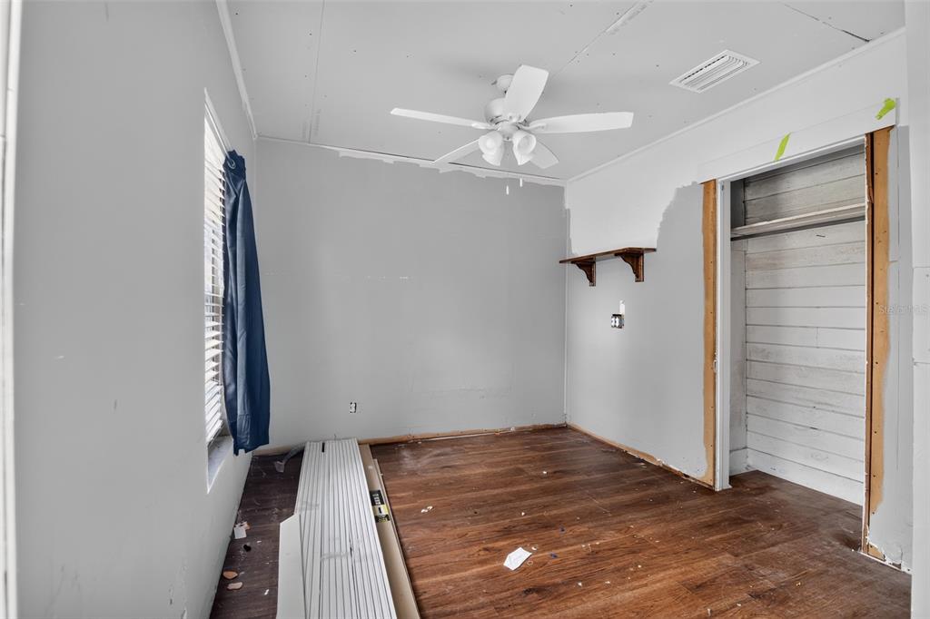 An unfinished bedroom features gray walls, wood-look flooring, a ceiling fan, and an open closet — 306 SE 2ND STREET, WILLISTON, FL