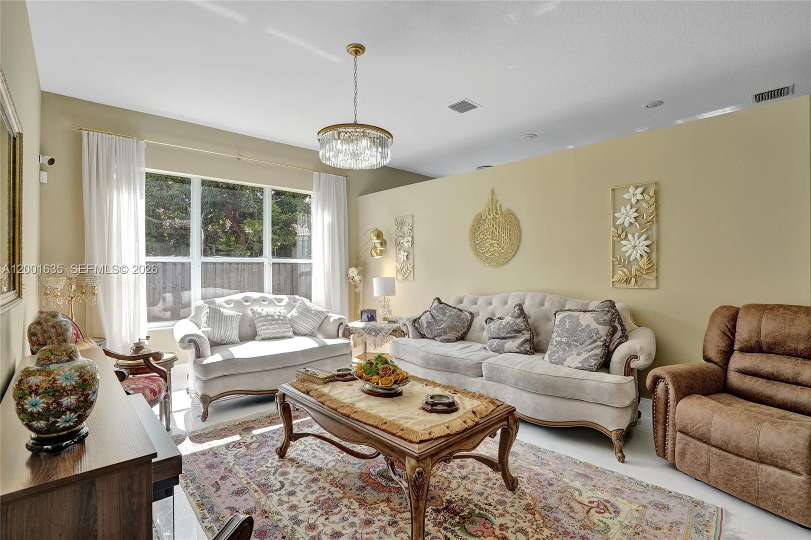 A living room features a crystal chandelier, beige walls, ornate furniture, and a patterned area rug — 4286 NW 42nd Ter, Coconut Creek FL 33073, COCONUT CREEK, FL