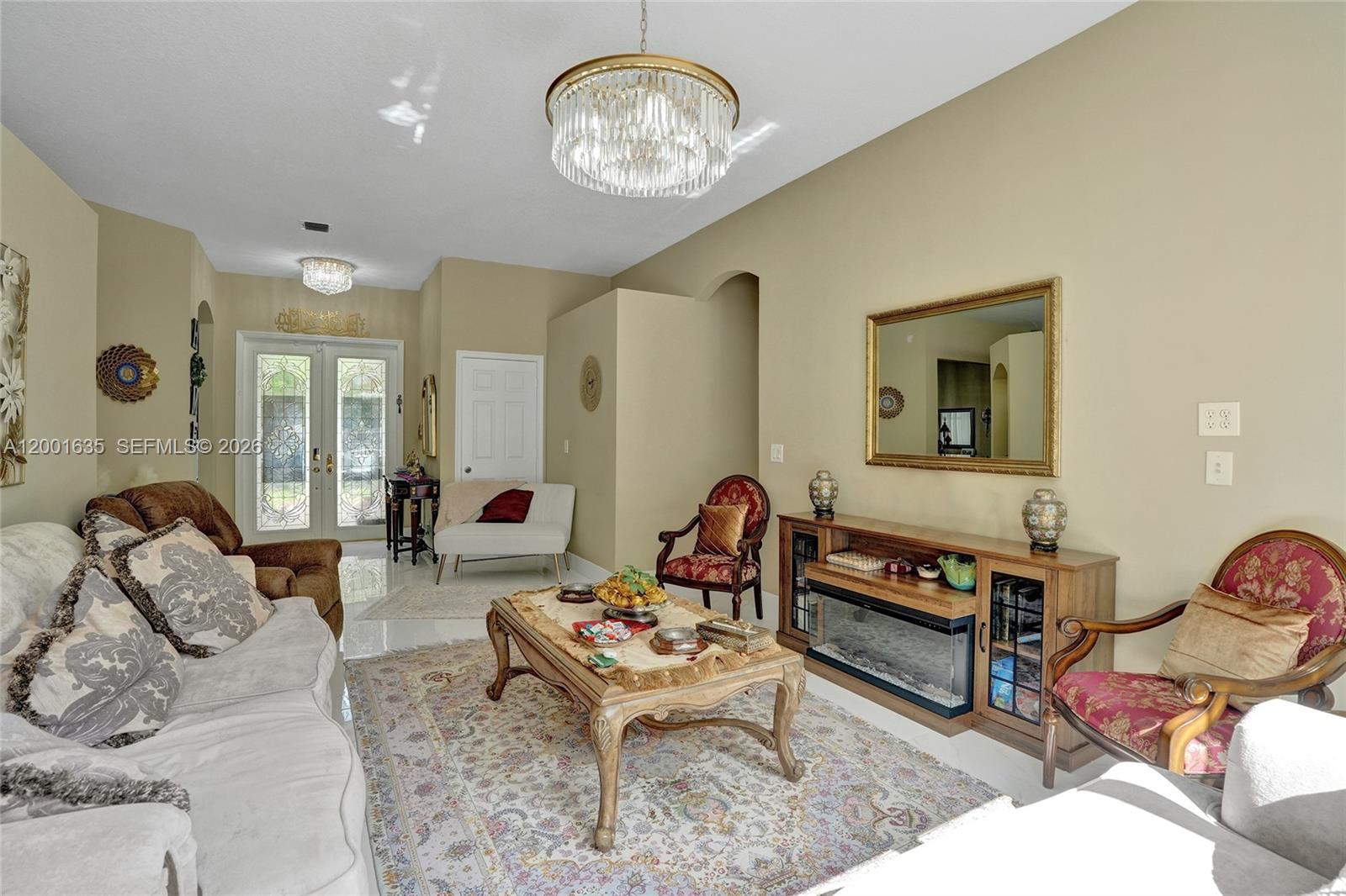 A living room features a crystal chandelier, a fireplace console, and traditional patterned furniture — 4286 NW 42nd Ter, Coconut Creek FL 33073, COCONUT CREEK, FL
