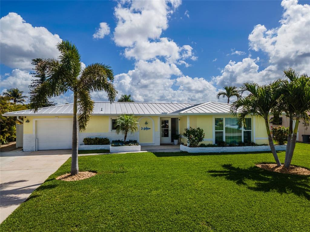 A single-story yellow house with a metal roof and palm trees in the front yard — 3517 SE 1ST AVENUE, CAPE CORAL, FL