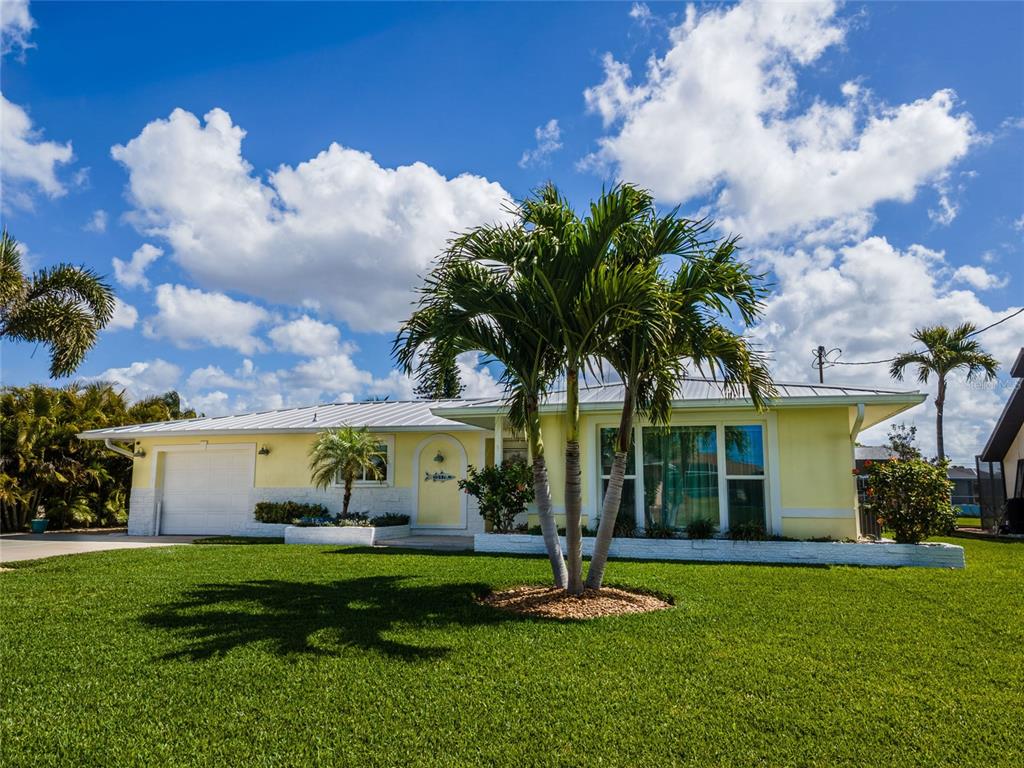 A yellow single-story house with a white metal roof and a palm tree in front — 3517 SE 1ST AVENUE, CAPE CORAL, FL