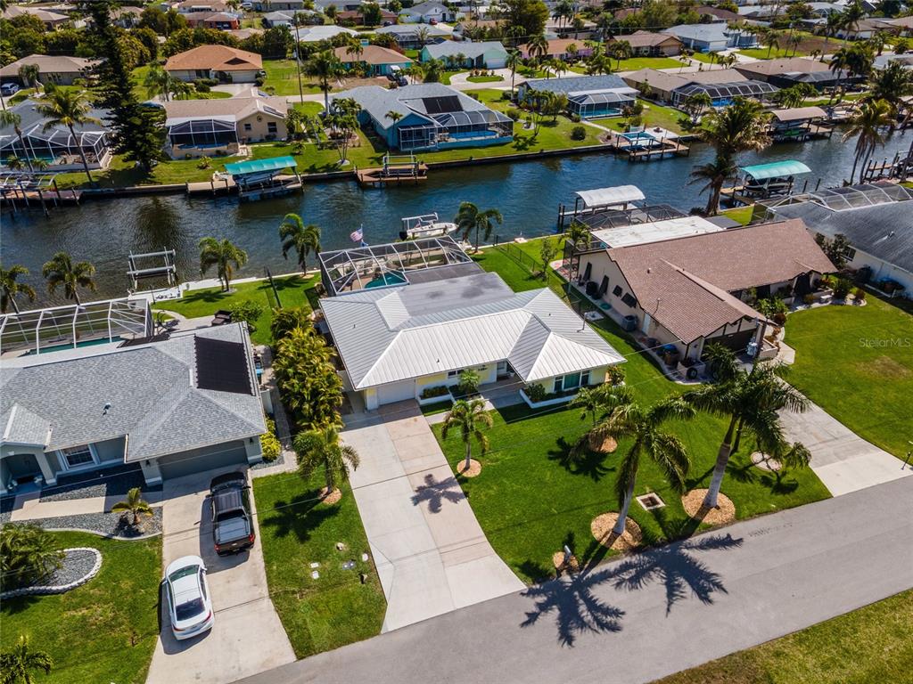 An aerial view shows a residential house with a metal roof, pool cage, and canal access — 3517 SE 1ST AVENUE, CAPE CORAL, FL