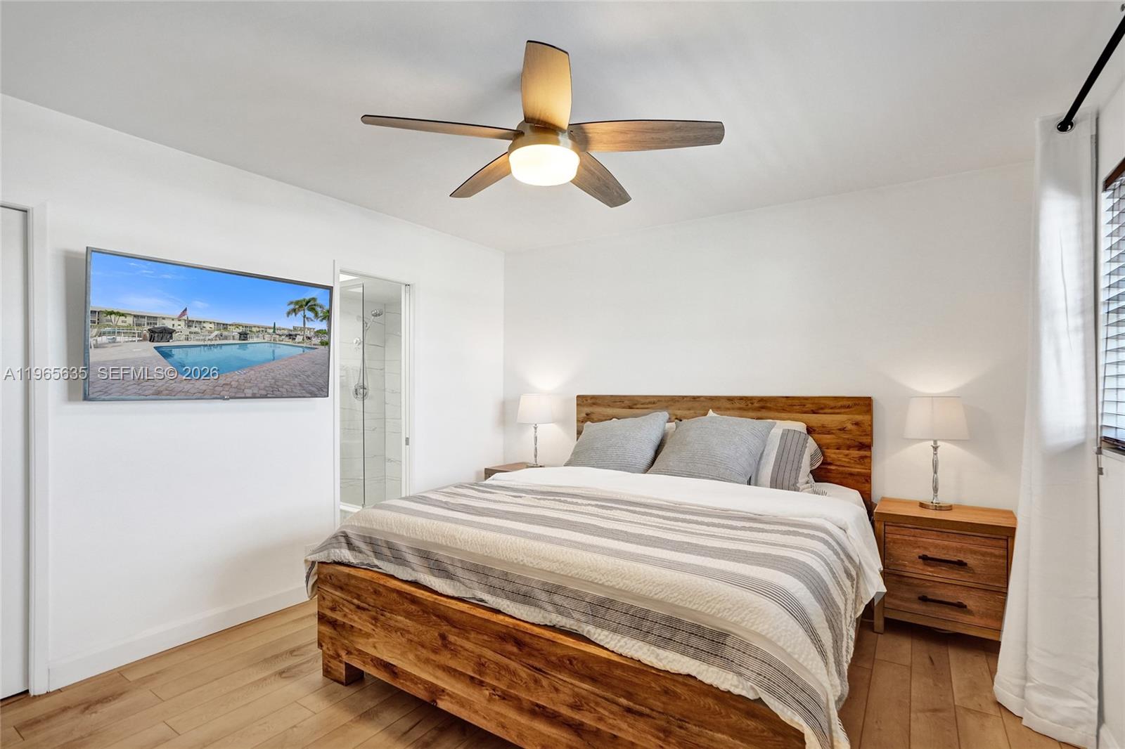 A bedroom features a wooden bed frame, a ceiling fan, and a wall-mounted television — 934 SE 9th Ave # 17, Pompano Beach FL 33060, POMPANO BEACH, FL