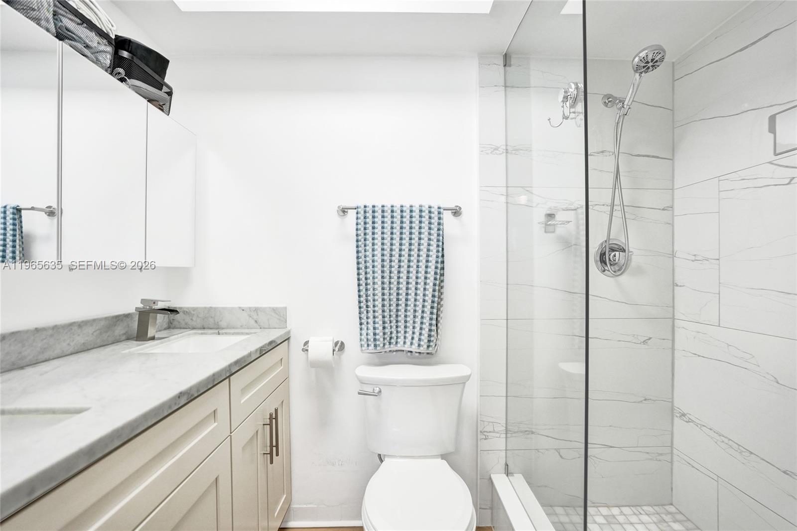 A bathroom features a marble-topped vanity, a white toilet, and a glass-enclosed walk-in shower — 934 SE 9th Ave # 17, Pompano Beach FL 33060, POMPANO BEACH, FL