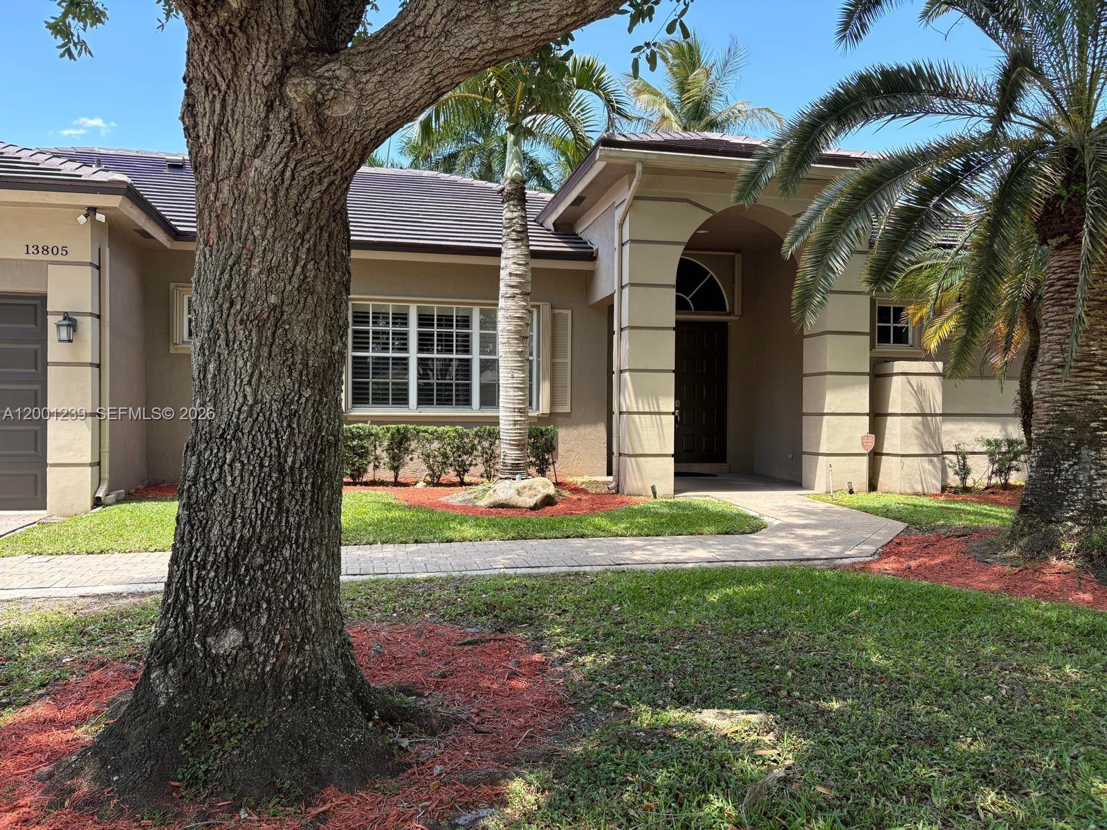 A single-story house with a tan stucco exterior, a dark roof, and a palm tree — 13805 SW 41st St, Davie FL 33330, DAVIE, FL