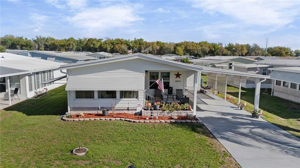 A single-story manufactured home with a white exterior, front porch, and attached carport — 36853 JODI AVENUE, ZEPHYRHILLS, FL