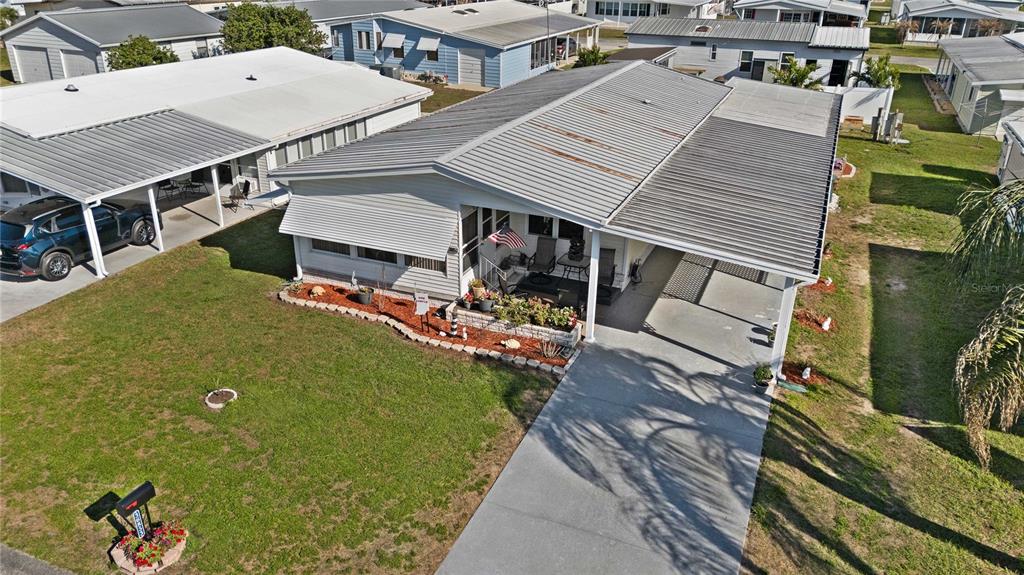 An aerial view shows a single-story mobile home with a metal roof and carport — 36853 JODI AVENUE, ZEPHYRHILLS, FL