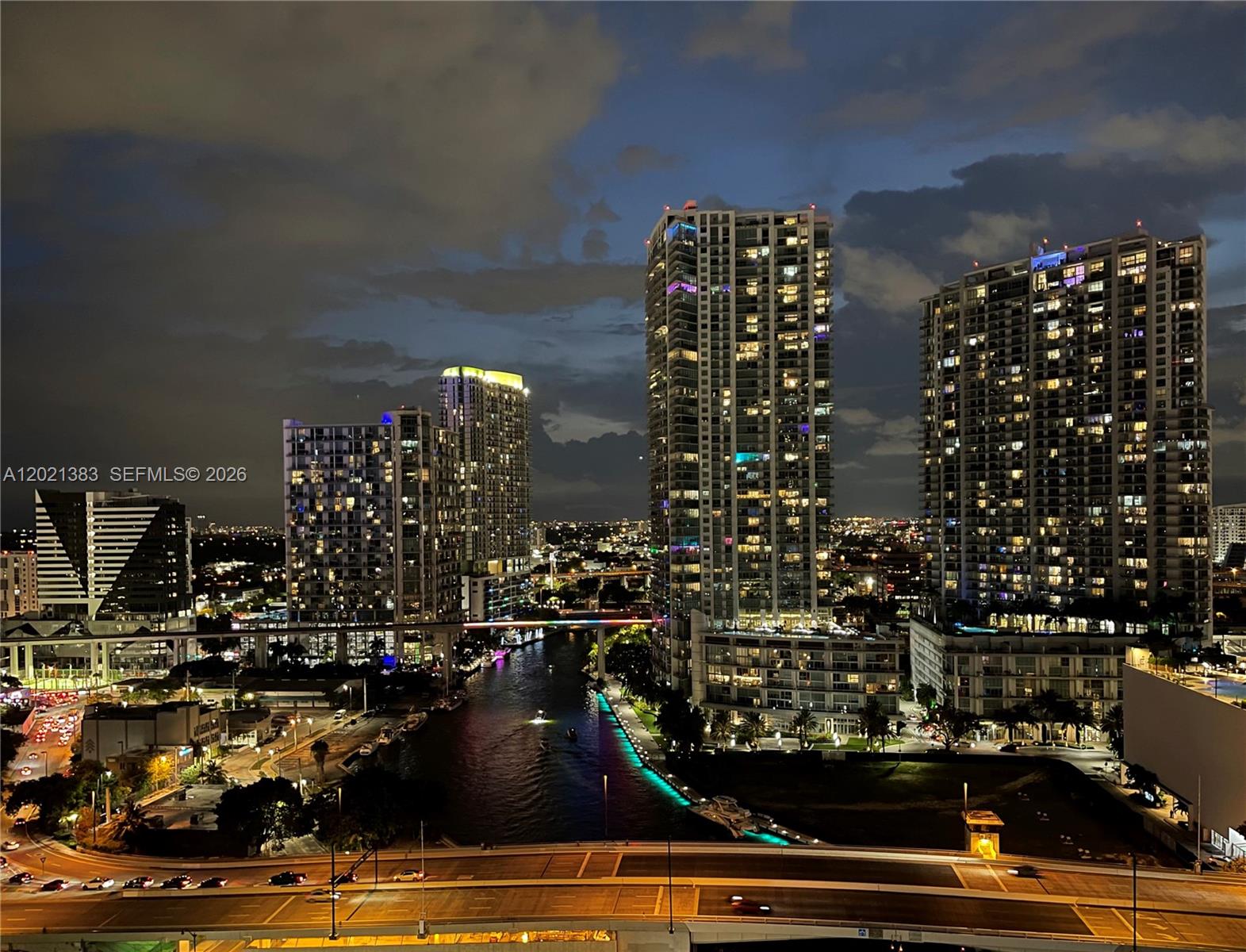 An elevated night view of a city skyline featuring illuminated high-rise buildings along a river — 31 SE 5th St # 2307, Miami FL 33131, MIAMI, FL