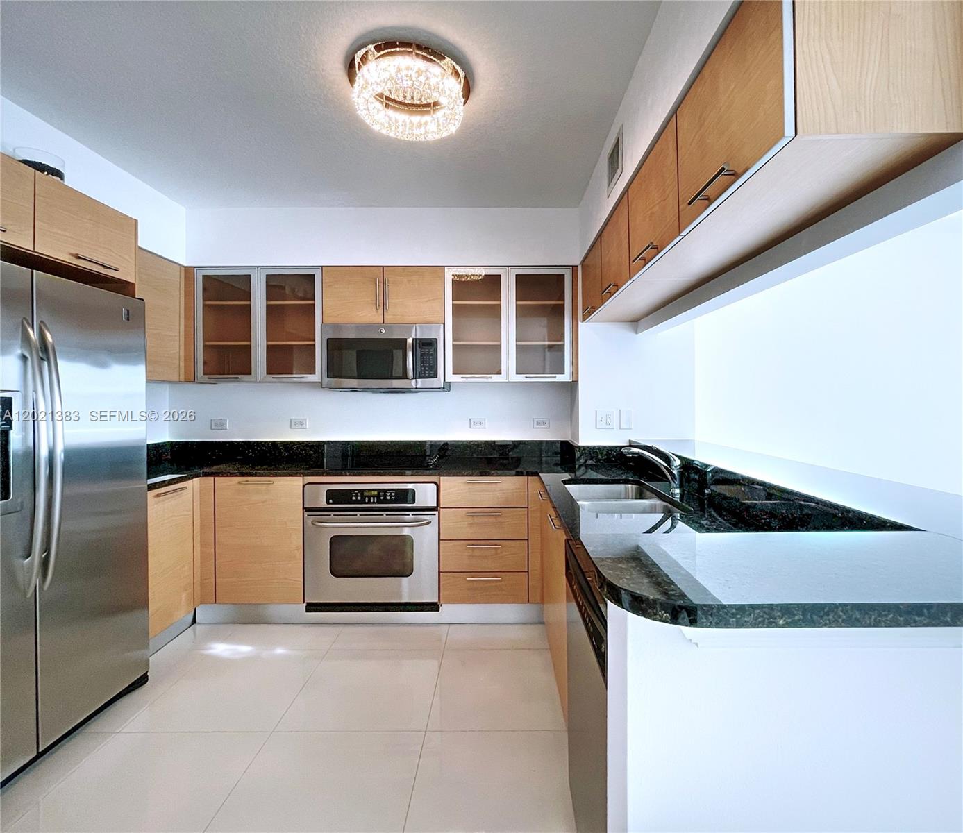 A kitchen features light wood cabinets, dark granite countertops, stainless steel appliances, and tile flooring — 31 SE 5th St # 2307, Miami FL 33131, MIAMI, FL