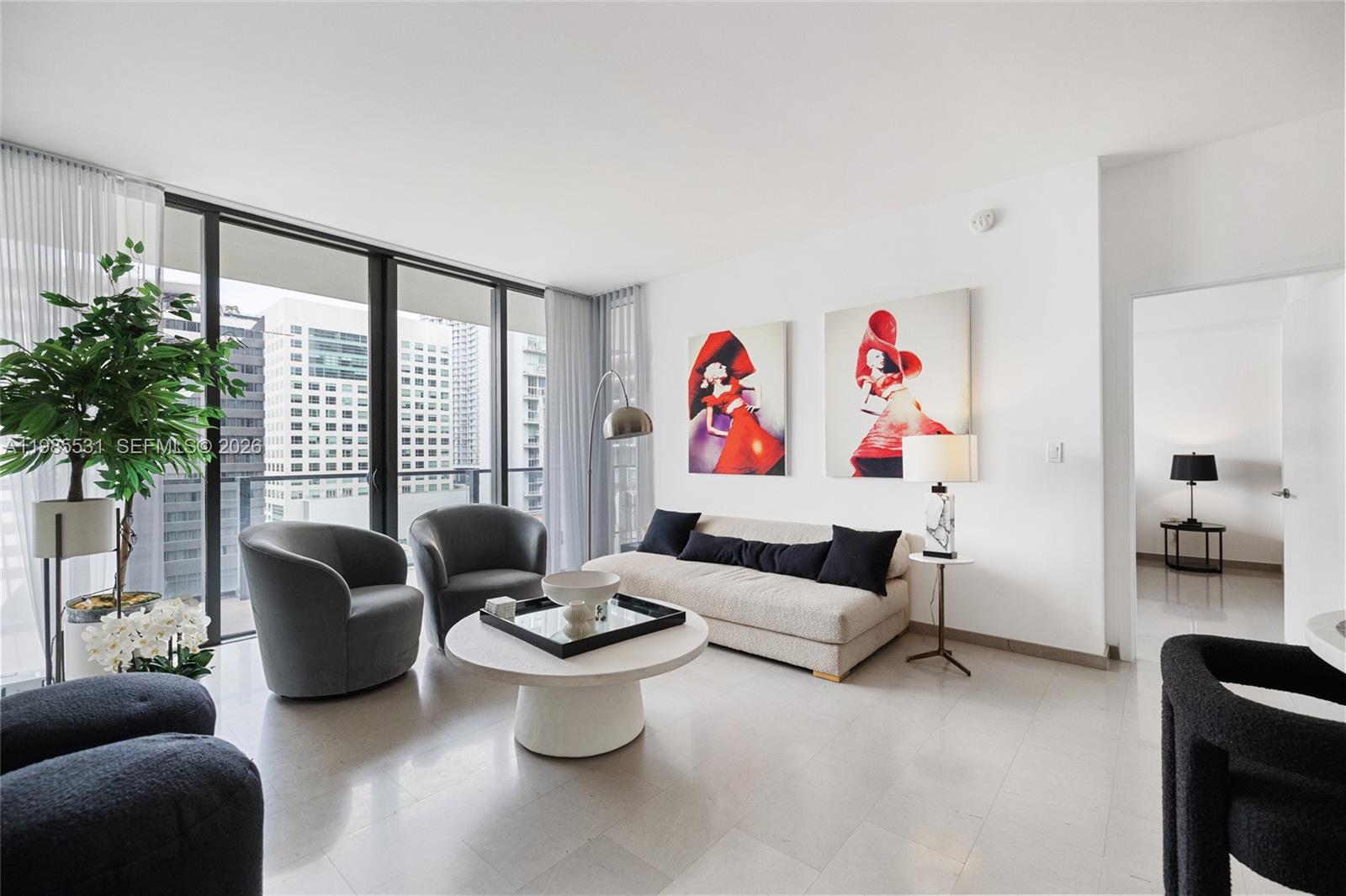 A modern living room features a beige sofa, two grey armchairs, and two red-themed paintings — 88 SW 7th St # 1010, Miami FL 33130, MIAMI, FL