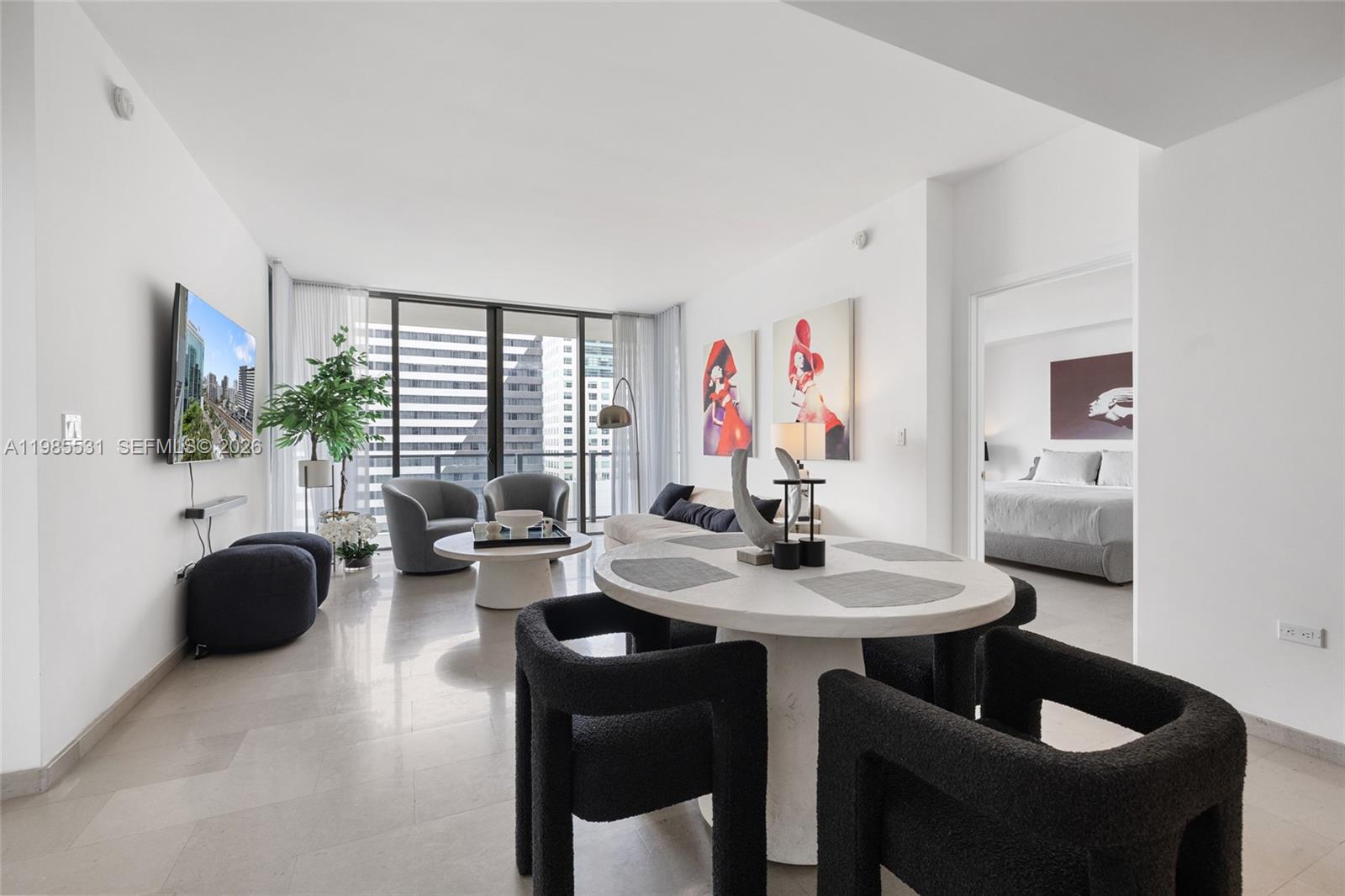 A modern living and dining area features a round table, black chairs, and floor-to-ceiling windows — 88 SW 7th St # 1010, Miami FL 33130, MIAMI, FL