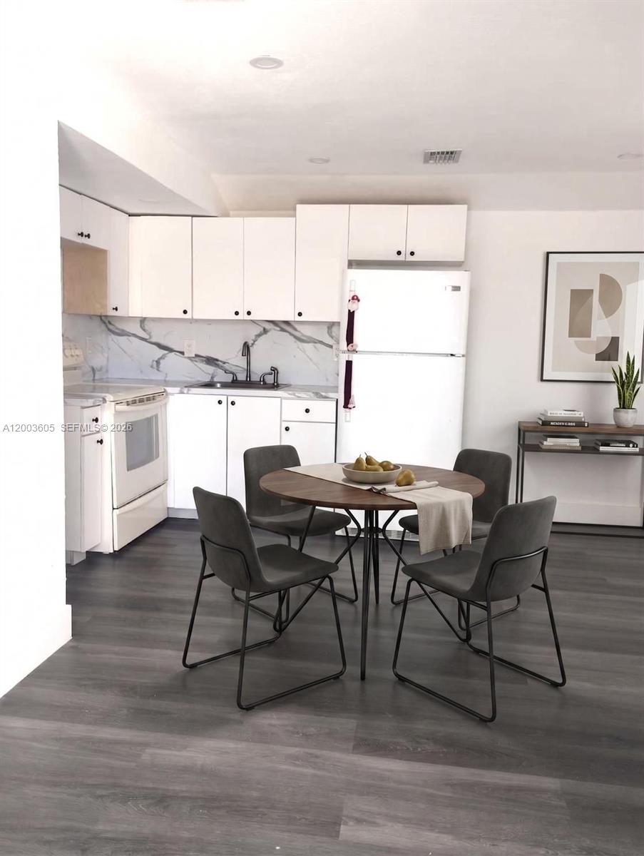 A kitchen with white cabinets, a marble-patterned backsplash, and a round dining table with chairs — 2971 NW 132nd Ter # B, Opa-Locka FL 33054, OPA-LOCKA, FL