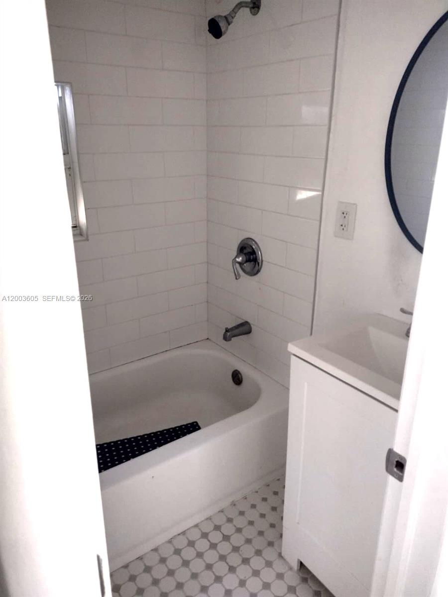 A bathroom features a white subway-tiled shower-tub combo, a vanity, and a patterned floor — 2971 NW 132nd Ter # B, Opa-Locka FL 33054, OPA-LOCKA, FL