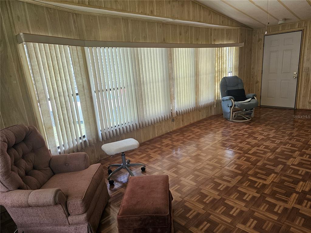 A living room features wood-paneled walls, parquet flooring, vertical blinds, and two armchairs — 198 SUNSET DRIVE, LAKE ALFRED, FL