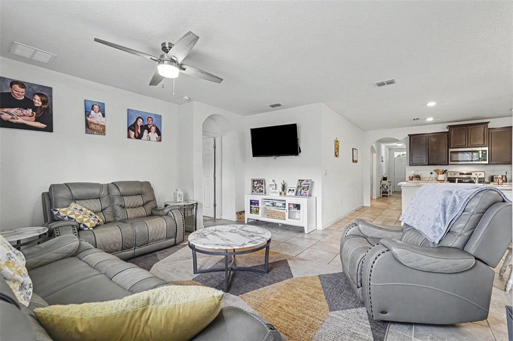 A living room features gray leather furniture, a marble-topped coffee table, and tile flooring — 1718 PACE DR NW, PALM BAY, FL