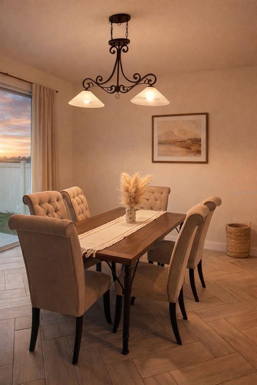 A dining room features a wooden table, upholstered chairs, a chandelier, and herringbone tile floors — 3678 GRAPPLER CIRCLE SE, PALM BAY, FL