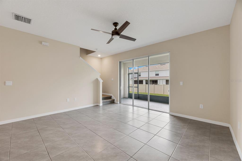 An empty living room with tile flooring, a ceiling fan, and sliding glass doors — 3507 MARIGOLD PATCH COURT, PLANT CITY, FL