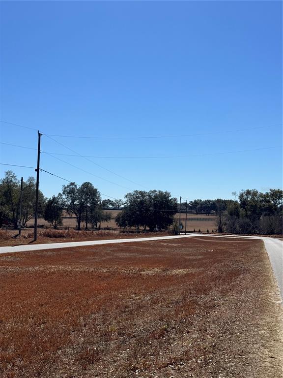 A vacant, grassy lot sits at the corner of two paved roads under a clear sky — 000 SW 150TH COURT, OCALA, FL