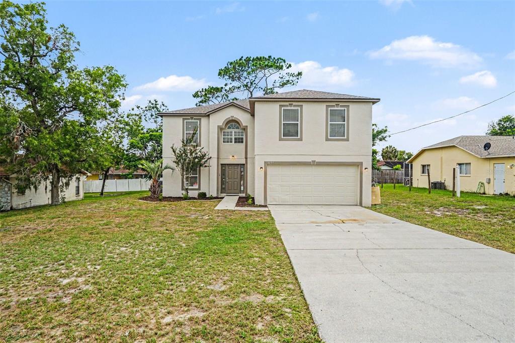 A two-story beige house with a two-car garage and a concrete driveway — 6197 HELMLY AVENUE, SPRING HILL, FL