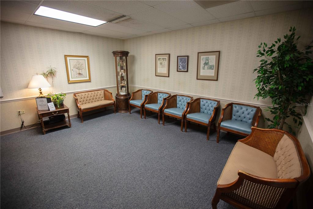 A waiting room features a carpeted floor, wallpapered walls, several chairs, and a display cabinet — 1201 FIFTH AVENUE N UNIT 302, ST PETERSBURG, FL