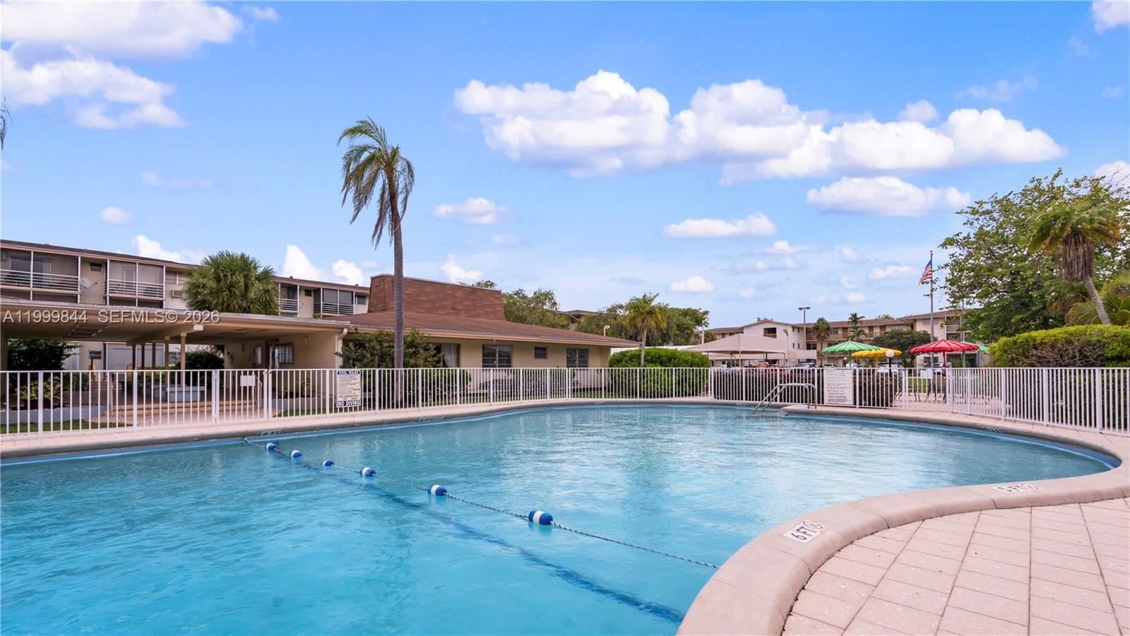 A swimming pool with a safety fence is surrounded by apartment buildings and palm trees — 16900 NE 14th Ave # 204, Miami FL 33162, MIAMI, FL